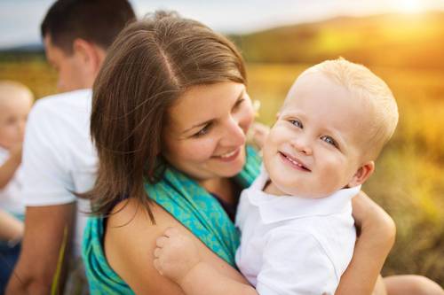 Quelle: fotolia.de Frau mit Kind auf dem Arm und Mann im Hintergrund